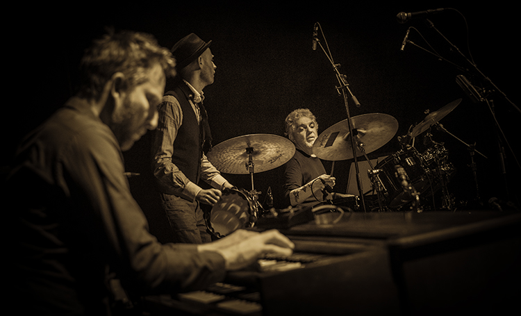 Sepia tone close-up photograph view of Blicher Hemmer Gadd music group members playing/performing their live music