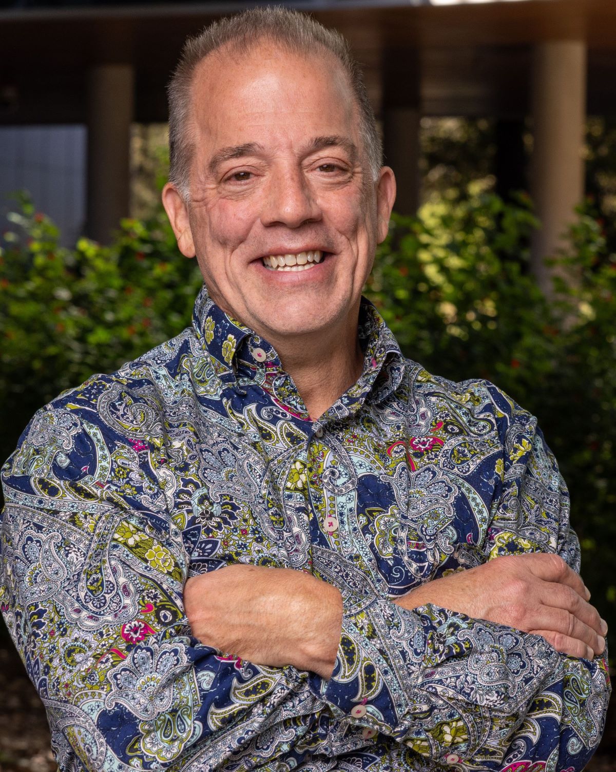 Portrait orientation photograph of Dr. Don Lucas, Ph.D. smiling and standing with his arms crossed in a multi-colored floral pattern (blue, green, magenta, black and white color shades) button-up dress shirt Portrait orientation photograph of Dr. Don Lucas, Ph.D. smiling and standing with his arms crossed in a multi-colored floral pattern (blue, green, magenta, black and white color shades) button-up dress shirt