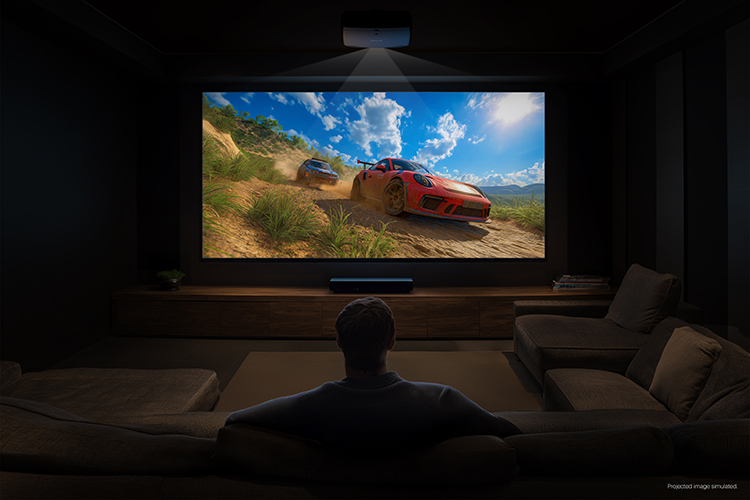 Digital promotional marketing landscape orientation image display of the Epson Pro Cinema LS9000 4K HDR Laser Projector being used in effect in a dimly dark shadow living room area projecting an image of dirt racing cars in a beautiful nature landscape topography with the back rear side view of a man sitting back on the couch watching this projected image with a small fine print at the right edge corner that says Projected image simulated