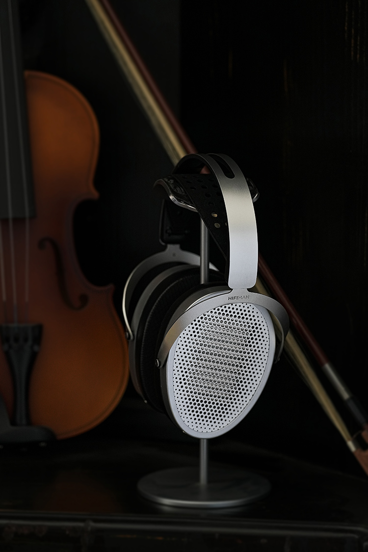 HIFIMAN Edition XV open-back planar headphone Side Angle View positioned on top of a headphone stand nearby a violin