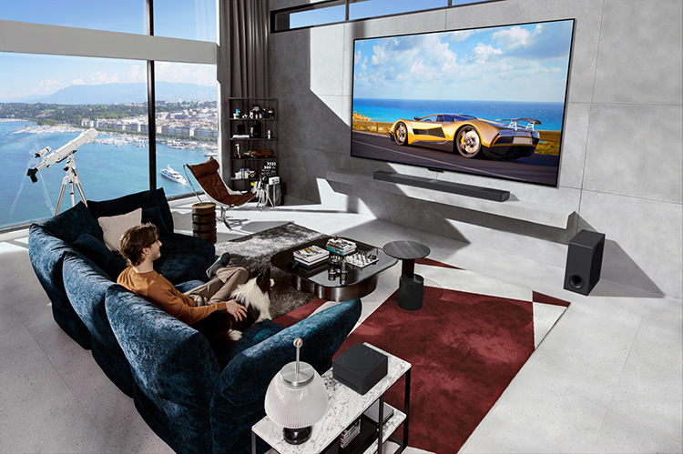 Man seated down in a living room watching a sports car on the LG Signature OLED M4 TV Model