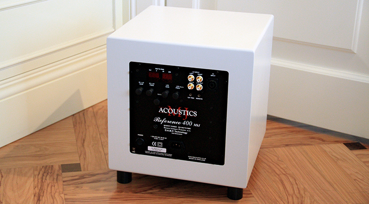 MJ Acoustics Reference 400 MkI Subwoofer White Satin Finish Rear View sitting on short black feet on a tiled floor; It is positioned near a partial white area of a wall border and white closed doorway