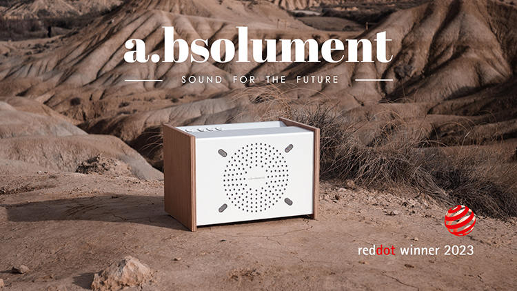 A.bsolument Prodige Bluetooth Speaker Angle View in a desert landscape environment background with a floating A.bsolument logo with the mantra Sound For the Future above the product and a reddot winner 2023 logo floating in the right bottom corner