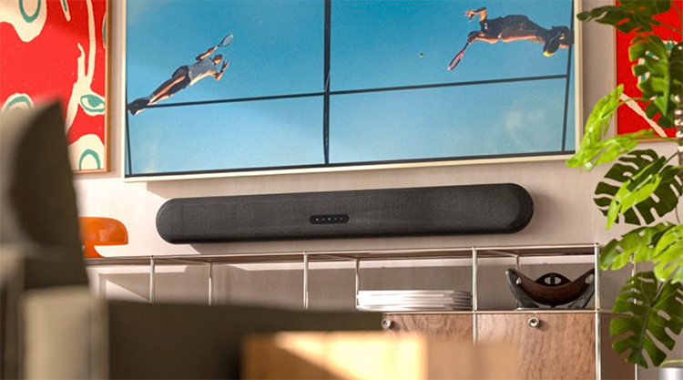 Digital image display landscape orientation view of a sleek Bluesound PULSE CINEMA – Black Soundbar mounted below a wall-mounted TV that is displaying an action shot of two tennis players; The soundbar is positioned on a black shelf, and the scene is a stylized living room with modern art and a plant