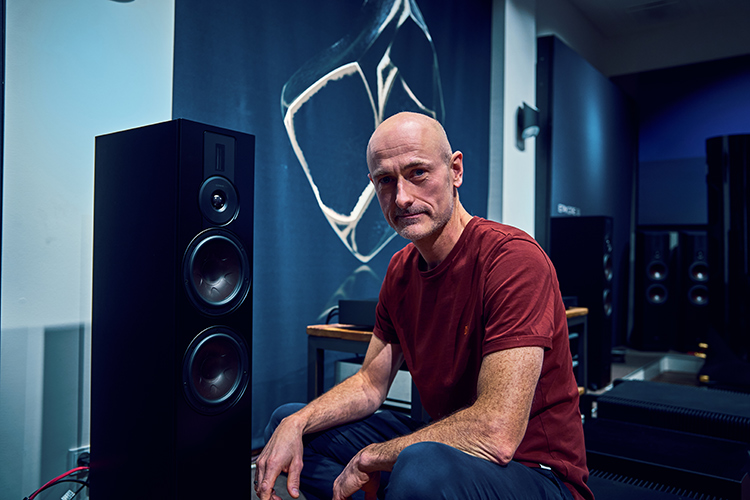 Krestian Pedersen, DALI Head of Product Management, seen looking directly at the camera while crouched nearby one of the DALI loudspeaker models