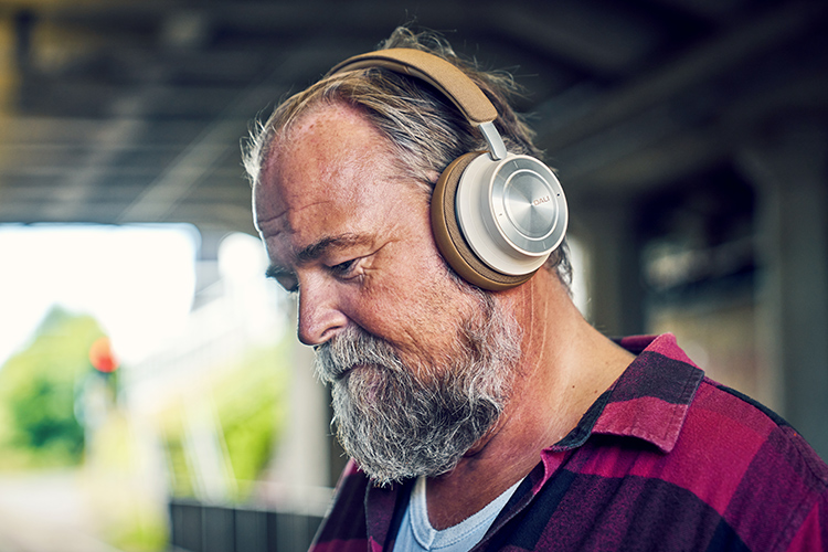 Bearded man looks down at the ground as he is listening to his DALI IO-8 Headphone Caramel White Finish