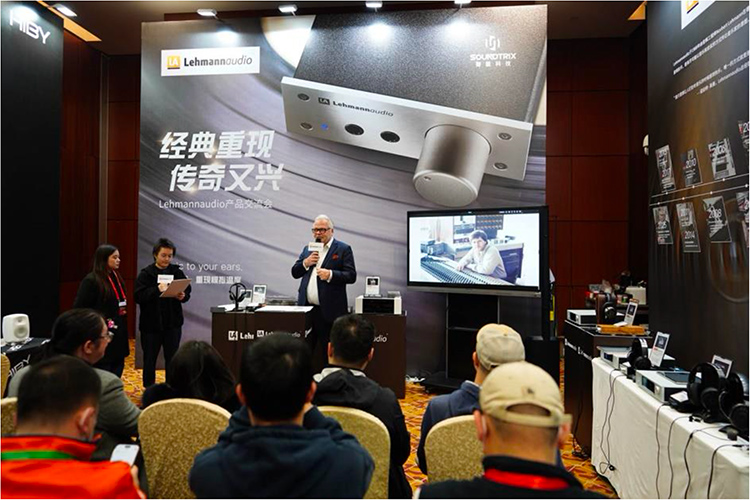 Portrait indoor photograph of the public listening to a Lehmannaudio audio brand exhibitor display product presentation showcase within 2024 Guangzhou International Headphones Expo at the Baiyun International Convention Center in Guangzhou, China