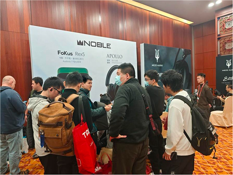 Portrait indoor photograph of the public trying out various audio demo products from audio company brands such as NOBLE and Meze Audio within the 2024 Guangzhou International Headphones Expo at the Baiyun International Convention Center in Guangzhou, China