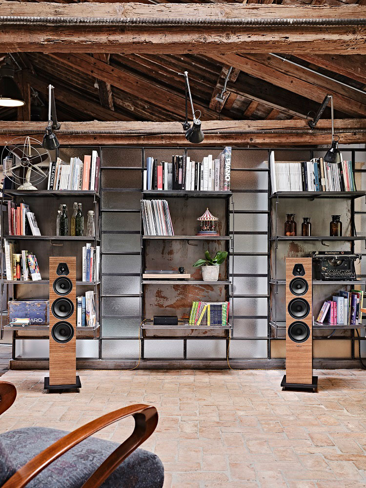 The Sonus faber Lumina V loudspeaker displayed in an industrial-styled living room with bookshelves