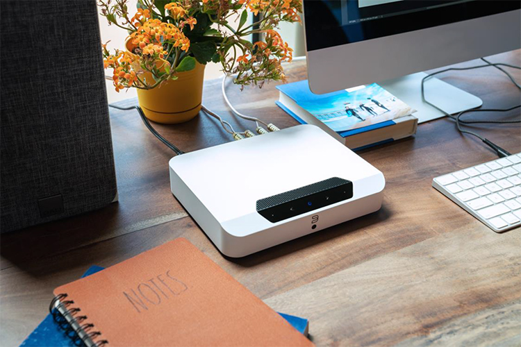 Bluesound POWERNODE EDGE wireless music streaming amplifier connected to speakers on a desktop