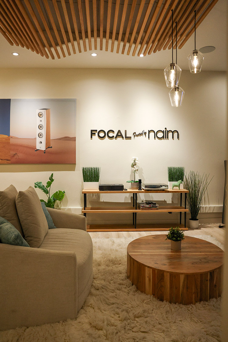 An interior landscape photograph of the Focal Powered by Naim retail space in Newport Beach featuring Focal Powered by Naim turntables in the showroom area located nearby a small sofa chair and a small round circular table